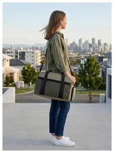 Femme portant un grand sac de voyage vert olive moderne dans un cadre urbain extérieur