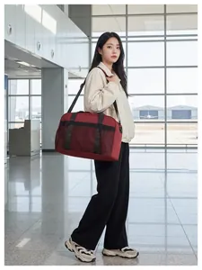 Modèle asiatique portant un grand sac de voyage rouge dans un aéroport moderne
