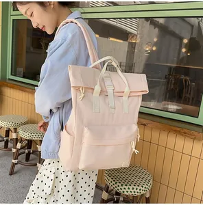 Large pink lightweight travel backpack shown worn by a model in a casual cafe setting