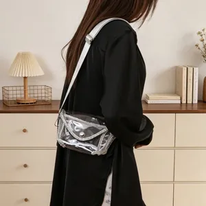 Detail view of a transparent PVC crossbody bag with rhinestone trim on a model.