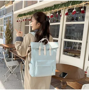 Close-up of a lightweight light blue travel backpack worn by a model in a cafe.