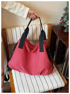 Close-up detail of a large red grid nylon tote bag held over a stylish wooden chair.