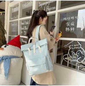 Lightweight light blue roll-top backpack for travel worn by a person in a casual setting