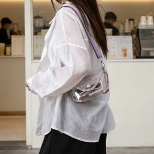 Close-up detail of a clear PVC crossbody bag with purple glitter trim worn by a model