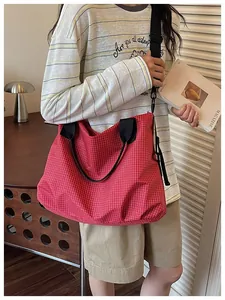 Large red grid nylon tote bag shown in a lifestyle commuter setting