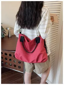Stylish large capacity red grid nylon tote bag worn by a person in a modern room.