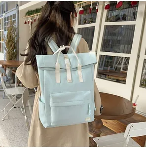 Lightweight mint green travel backpack worn by a person in a cozy cafe setting