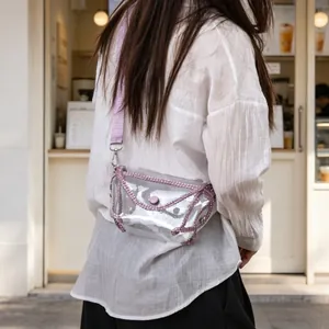 Close-up view of a trendy transparent PVC crossbody bag with pink rhinestone trim detail