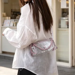 Detail of transparent PVC crossbody bag with elegant pink rhinestone trim worn by model