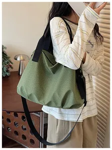 Detailed view of a green grid nylon tote bag carried on a fashion model's shoulder