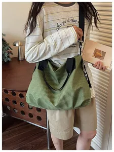 Close-up detail shot of a large green checkered nylon tote bag carried by a model.