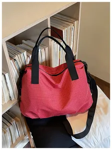 Close-up detail of a large red grid nylon tote bag placed naturally in a wooden bookshelf setting.