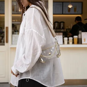 Trendy model wearing a transparent PVC crossbody bag with rhinestone trim in a lifestyle cafe