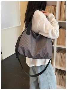 Detailed view of a large plaid nylon tote bag worn over the shoulder in a library setting.