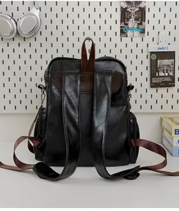 Back view of a vintage black leather backpack with brown straps in a modern setting