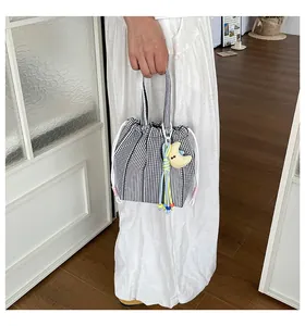 Detalle de un bolso de cuadros negros minimalista con cordón y un lindo amuleto de luna