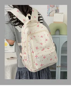 Vue arrière d'une fille portant un sac à dos blanc cassé avec des motifs de nœuds roses