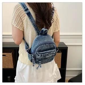 Back view of a woman wearing a blue washed denim backpack with adjustable straps.