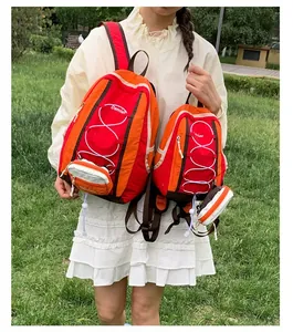 Foto al aire libre de una mujer con mochilas de senderismo rojas y naranjas de dos tamaños