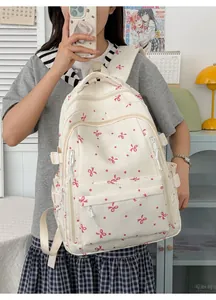 Vue détaillée du sac à dos blanc avec joli motif de nœuds roses et compartiments