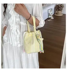 Vista de estilo de vida de un bolso bombonera de cuadros amarillos con cordón, llevado por modelo.