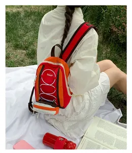 Vista trasera de una mochila ligera roja y naranja para senderismo llevada por una modelo