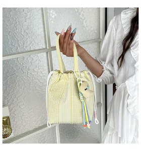 Primer plano de un bolso de cubo con cordón a cuadros amarillos y blancos de una modelo