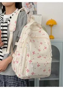 Vue de côté d'un grand sac à dos blanc avec des nœuds roses porté par un mannequin