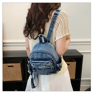 Stylish women's washed blue denim backpack shown from a back-view on a fashion model