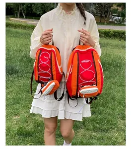 Dos tamaños de mochilas de senderismo naranja vibrante sostenidas por una modelo