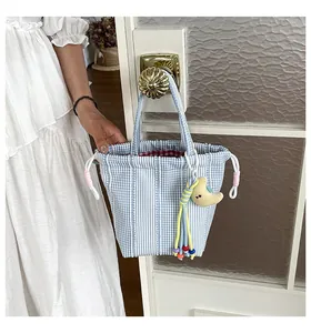 Elegante bolso tipo cubo de cuadros a rayas azules y blancas colgado del pomo vintage.