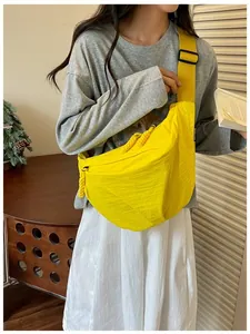 Dettaglio lifestyle di una borsa a tracolla leggera in nylon giallo su un modello