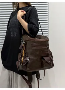 Detailed view of a vintage brown faux leather biker style shoulder bag worn by a model