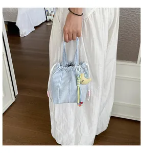 Primer plano de un bolso de cubo con cordón y cuadros vichy azules con colgante