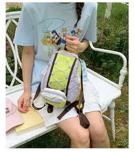 Primer plano de una mochila de senderismo verde lima y lavanda sostenida por una modelo
