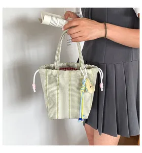 Detalle de bolso saco de cuadros verdes con cordón blanco y un bonito amuleto suave