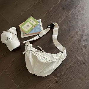 Borsa a tracolla minimalista in nylon bianco per donna su sfondo di legno scuro