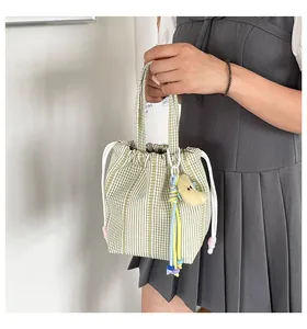 Primer plano de bolso de mano de cuadros verdes y blancos con cordón para mujer.