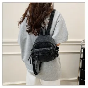 Close-up of a stylish black denim mini backpack worn by a model in a casual setting