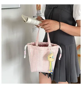 Vista detallada de un bolso bombonera de rayas rosas con cordón sostenido por una modelo.