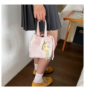 Detalle de un bolso saco a rayas rosas y blancas con colgante de luna sostenido a mano