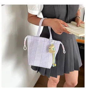 Detalle de un bolso de tela de cuadros morados con un colgante de luna y falda plisada.
