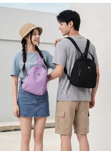 Dettaglio lifestyle di un uomo e una donna che indossano mini zaini viola e neri all'aperto.