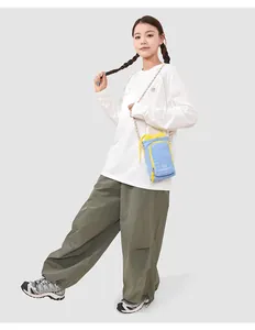 Asian female model wearing a light blue crossbody phone bag with yellow drawstring detail.