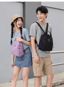 Modelli asiatici mostrano mini zaini impermeabili viola e neri alla moda all'aperto