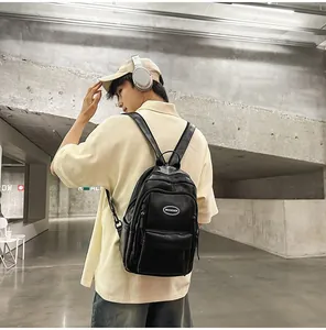 Male model showcasing a minimalist black PU leather backpack in a modern urban gallery setting.