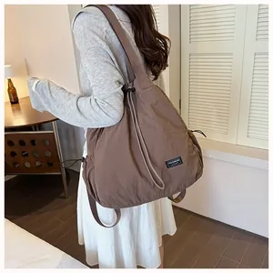 Vista posteriore di una grande borsa a tracolla marrone in nylon impermeabile con coulisse
