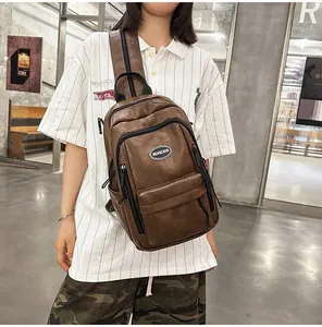 Detail view of brown faux leather sling bag worn by model in casual urban setting.