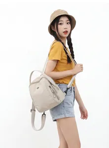 Modella asiatica con un elegante mini zaino beige impermeabile per il pendolarismo quotidiano.