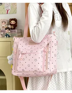 Kawaii pink tote bag with star pattern and cute cat pendant shown on shoulder